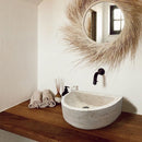 Troia Light Travertine Half Round Wall-mount Bathroom Sink (W)10" (L)16" (H)6" installed bathroom above wooden vanity and brown hand towels room scent Troia Light Travertine Half Round Wall-mount Bathroom Sink (W)10" (L)16" (H)6" installed bathroom above wooden vanity and brown hand towels room scent