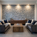 Modern living room with stone wall, gray sofas, and wooden coffee table. Bluestone Marble 3D Ledger Stone Panel 6"x24"