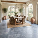 Dining room with wooden table, chairs, and large windows. Bluestone Sandblasted Brushed French Pattern Set Marble Tile
