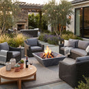 Outdoor patio with fire pit, chairs, and a wooden table in a garden setting. Bluestone Marble Natural Stone Fire Pit 24" x 24" x 8"