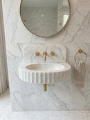 Marble sink with gold fixtures in a bathroom setting. Carrara White Marble Wall-mount Bathroom Sink Fluted Front (W)16" (L)24" (H)6"