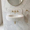 Marble sink with gold fixtures in a bathroom setting. Carrara White Marble Wall-mount Bathroom Sink Fluted Front (W)16" (L)24" (H)6"