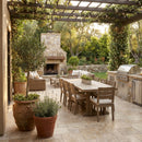 Outdoor patio with dining table, chairs, fireplace, and grill area. Country Classic Travertine Tumbled Pavers