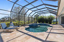 Pool area with lounge chairs and a screened-in enclosure under a clear blue sky. Denizli Beige Filled &amp; Tumbled Pavers (3 cm Thick)