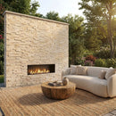 Outdoor living space with stone fireplace, sofa, and coffee table in a garden setting. Diana Royal Ledger 3D Panel – 6" x 24" Honed Natural Marble Wall Tile