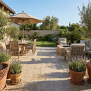 Outdoor patio with wooden furniture, table, and umbrella in a garden setting. Meandros Walnut Travertine Pattern Pavers