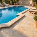 Pool area with lounge chairs and potted plants on a sunny day Travertine Miletos Ivory Tumbled Pavers