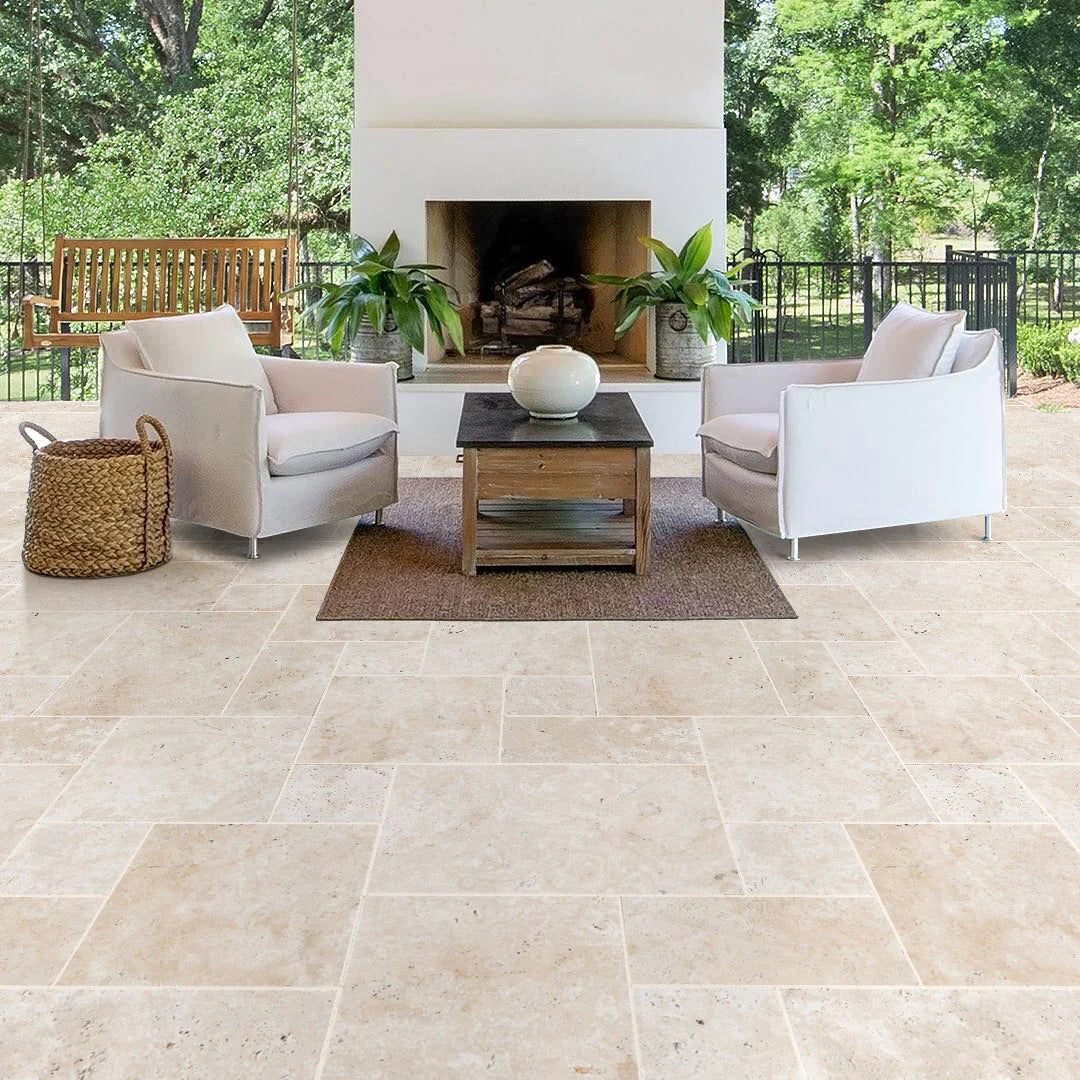 Outdoor patio with beige tiles, white chairs, and a small table. Travertine Miletos Ivory Tumbled Pavers