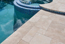 Close-up of a poolside area with tiled pool and stone patio. Ivory Moderno Travertine Filled and Tumbled Pavers