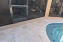 Outdoor patio area with a pool and sliding glass door. Ivory Moderno Travertine Filled and Tumbled Pavers