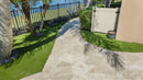 Paved patio area with grass and a fence in the background. Ivory Moderno Travertine Filled and Tumbled Pavers