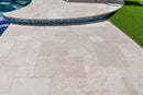 Beige stone tiles on a patio with a pool and grass in the background