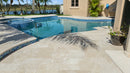 Pool area with tiled deck and palm tree shadow. Ivory Moderno Travertine Filled and Tumbled Pavers