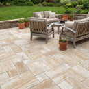 Outdoor patio with stone tiles, wooden furniture, and potted plants. Patara Beige Vein-cut Tumbled Travertine Pavers