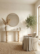 Nestled corner of a room with a round mirror, small table, chair, and potted plant.