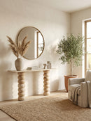 Modern interior with a round mirror, console table, and potted plant.