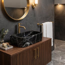 Modern bathroom with marble sink, wooden vanity, and gold fixtures.