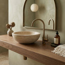 Bathroom vanity with stone sink, bronze faucet, and decorative items. Beige Travertine Natural Stone Vessel Sink Honed and Filled  (D)16" (H)6"