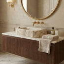 Bathroom vanity with marble sink, gold fixtures, and towels.