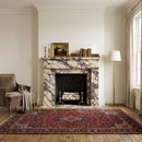 Living room with marble fireplace, armchair, and patterned rug.
