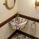 Small marble sink with gold fixtures in a bathroom setting
