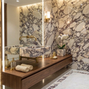 Modern bathroom with marble wall, sink, and wooden vanity.