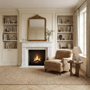 Cozy living room with fireplace, armchair, and bookshelves.