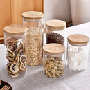 Clear glass storage jars with bamboo lids for kitchen organization by Decorbites