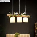 GobekUsa Industrial 3-Light Hanging Pendant for Coffee Shop with Milky Glass Cylinder, Wooden Stick, and Bird Accent