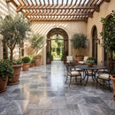 Outdoor patio with a dining table, chairs, and potted plants in a Mediterranean-style courtyard. Silver Shadow Marble Tumbled Pavers (3cm Thickness)