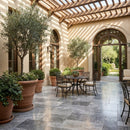 Outdoor patio area with tables, chairs, and potted plants under a pergola. Silver Shadow Marble Tumbled Pavers (3cm Thickness)