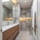 Modern bathroom with wooden vanity, glass shower enclosure, and towel rack.