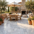 Outdoor patio with wooden furniture, umbrella, and fireplace. Solto White Marble Leathered Pavers