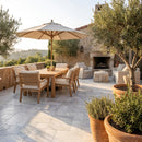 Outdoor patio with wooden furniture, umbrella, and fireplace. Solto White Marble Leathered Pavers